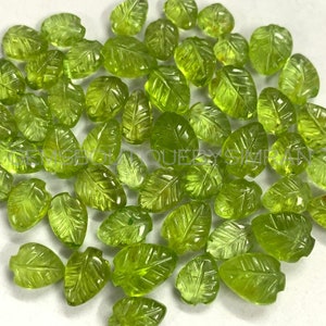 Può includere: Una collezione di perline di peridoto verde a forma di foglia. Le perline sono intagliate con dettagli intricati e hanno una finitura lucida.