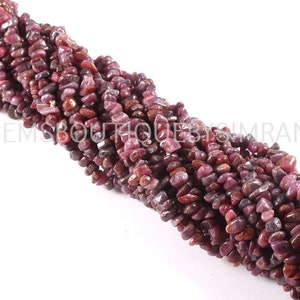 May include: A strand of small, irregular, red-purple gemstone beads. The beads are chip shaped and have a rough, natural finish.