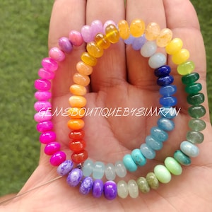 May include: A rainbow of gemstone beads strung on a wire. The beads are in order of the colours of the rainbow, starting with red and ending with violet. The beads are all about 1.2 cm in diameter.
