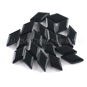May include: A pile of black diamond-shaped gemstones. The gemstones are faceted and have a glossy finish.