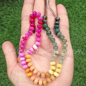 May include: A multi-colored gemstone bead necklace with pink, orange, yellow, and green beads. The necklace is strung on a thin cord and has a tassel at the end.