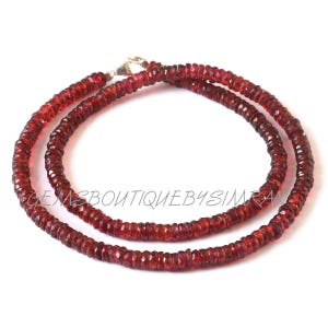 May include: A red gemstone necklace made of small, faceted beads. The necklace is double-stranded and has a silver clasp.