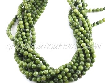 May include: A strand of green jade beads, each bead is round and smooth. The beads are strung on a clear thread and are approximately 6mm in diameter.
