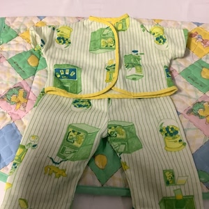 Puede incluir: Un pijama a rayas verde y amarillo con estampado de máquina de chicles. La parte superior tiene un ribete amarillo y los pantalones tienen un ribete verde.
