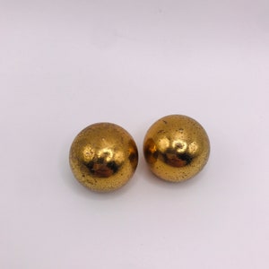 May include: A pair of gold-toned round earrings. The earrings have a textured surface.