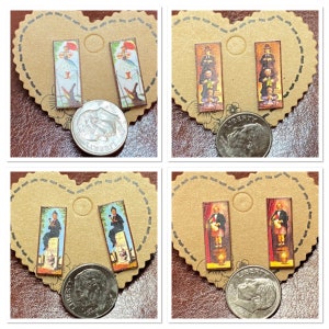 May include: Four pairs of rectangular stud earrings with different vintage-style illustrations. The earrings are on brown heart-shaped cards. The illustrations include figures with umbrellas, a man with a top hat, and a man in a suit.