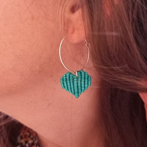 Puede incluir: Pendiente de aro plateado con un dije en forma de corazón turquesa.