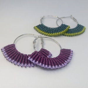 May include: A pair of silver hoop earrings with a purple and lavender fringe, and a pair of silver hoop earrings with a green and yellow fringe.