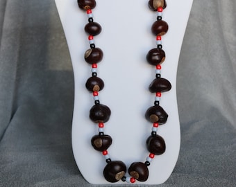 May include: A necklace made of brown buckeye nuts with red, white, and black beads.