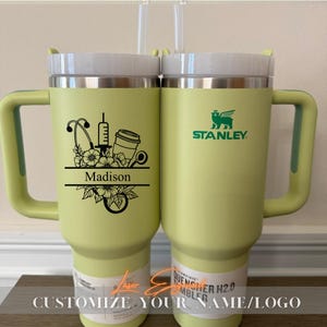 Close-up of a personalized 40oz powder-coated tumbler with a handle and straw. The laser engraving features a custom name in elegant script, a heart-shaped stethoscope design, and motivational nurse affirmations. The tumbler is shown in a professional setting, highlighting its durable finish and large capacity. Perfect gift for nurses and medical staff