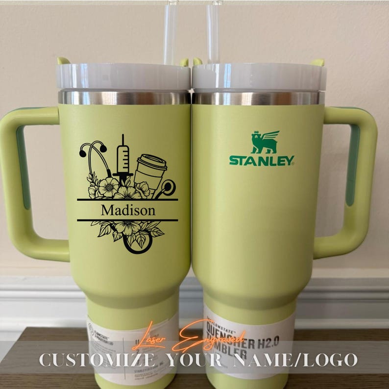 Close-up of a personalized 40oz powder-coated tumbler with a handle and straw. The laser engraving features a custom name in elegant script, a heart-shaped stethoscope design, and motivational nurse affirmations. The tumbler is shown in a professional setting, highlighting its durable finish and large capacity. Perfect gift for nurses and medical staff