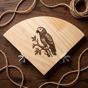 May include: A triangular light-colored wooden corner shelf featuring a dark brown laser-engraved illustration of an African Grey parrot perched on a branch. The shelf includes two metal mounting brackets with wing nuts on the bottom corners.