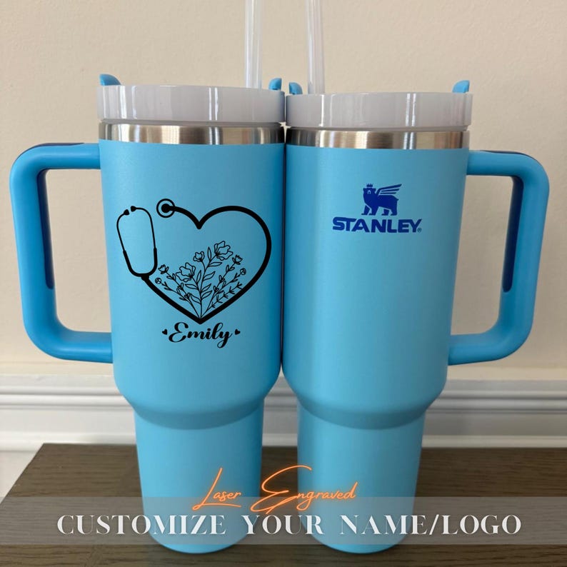 Close-up of a personalized 40oz powder-coated tumbler with a handle and straw. The laser engraving features a custom name in elegant script, a heart-shaped stethoscope design, and motivational nurse affirmations. The tumbler is shown in a professional setting, highlighting its durable finish and large capacity. Perfect gift for nurses and medical staff