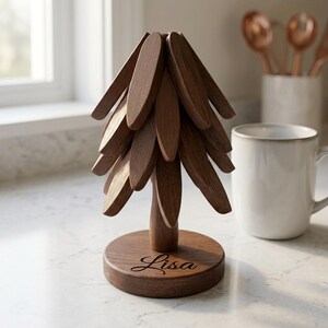 May include: A dark brown wooden tree-shaped stand with multiple layered, oval-shaped branches extending from a central trunk. The circular base features the name Lisa engraved in a cursive script font on the front surface of the wood.