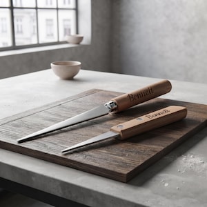 May include: Two kitchen tools with light brown wooden handles, each engraved with the name Bennett. The tools feature silver-colored metal blades and are positioned on a dark brown wooden cutting board. The handles have a smooth, cylindrical shape.