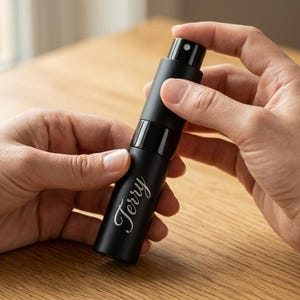 May include: A matte black cylindrical spray bottle featuring the name Terry engraved in a white cursive script. The atomizer has a black cap and a visible spray nozzle at the top, designed for dispensing liquids in a fine mist application.