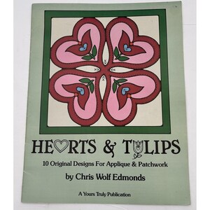 May include: A book cover titled "Hearts & Tulips" featuring a four-leaf clover design made of pink hearts and green leaves. The cover also includes the text "10 Original Designs For Applique & Patchwork" and the author's name.