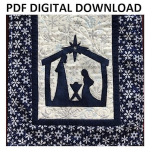 Pode incluir: Uma tapeçaria de parede acolchoada branca e azul com uma silhueta azul da cena da natividade. O fundo é um tecido branco com um padrão de floco de neve. A borda é um tecido azul com um padrão de floco de neve.