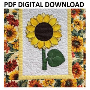 May include: A digital download PDF pattern for a quilted sunflower with a green leaf. The sunflower is yellow with a brown center and is surrounded by a yellow border. The background is white with a quilted pattern.