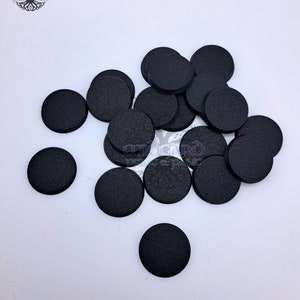 Può includere: Un gruppo di 18 basi rotonde in plastica nera per miniature. Le basi sono testurizzate e hanno un bordo leggermente rialzato.