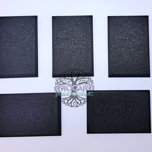 Könnte beinhalten: Fünf schwarze quadratische Kunststoffsockel mit einer strukturierten Oberfläche. Die Sockel sind etwa 5 cm x 5 cm groß.