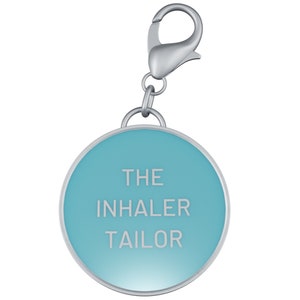 May include: A silver keychain with a blue round tag that says "THE INHALER TAILOR" in white text.