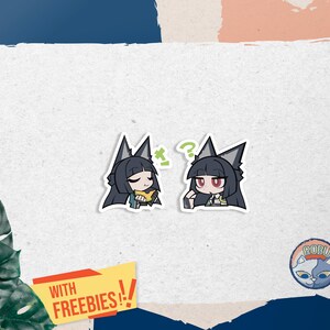 May include: Two anime-style stickers featuring a character with black hair and wolf ears. One sticker shows the character holding a yellow object, the other with a question mark. The stickers are on a white background with a "WITH FREEBIES!!" banner.