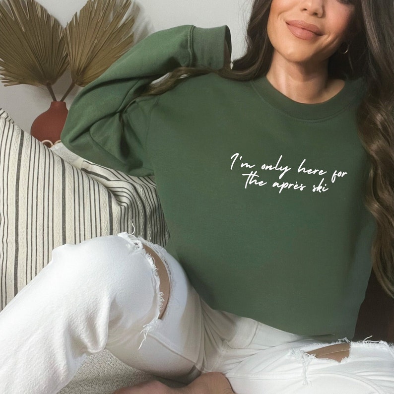 May include: A green cropped sweatshirt with the text "I'm only here for the apres ski" in white.