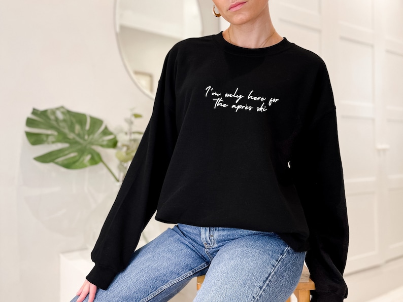 May include: Black sweatshirt with white text that reads "I'm only here for the apres ski".