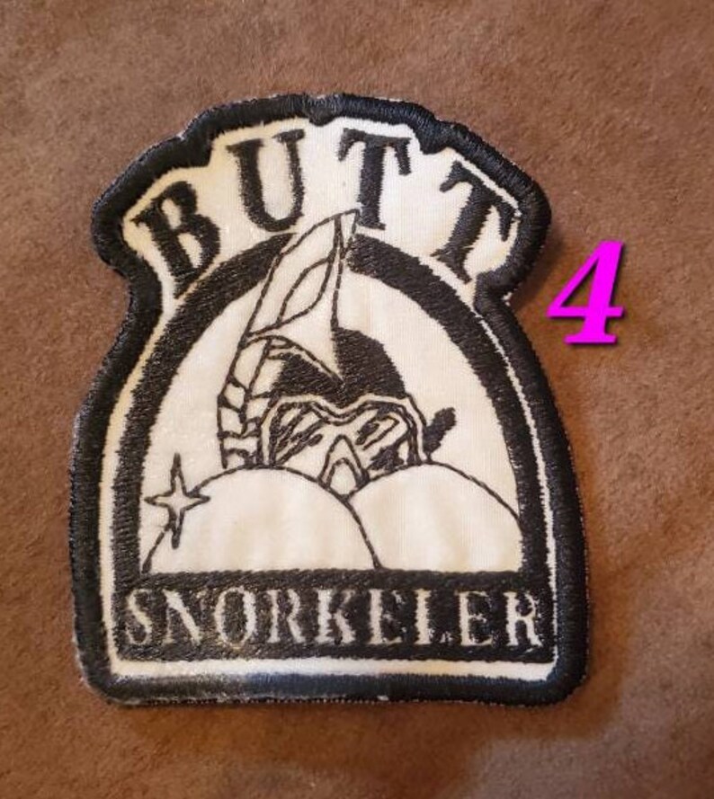 Puede incluir: Parche bordado en blanco y negro con el texto "Butt Snorkeler" y una imagen de dibujos animados de una persona con un snorkel y equipo de buceo.