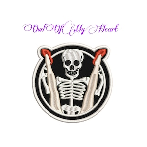 Puede incluir: Parche bordado con un esqueleto con las piernas cruzadas y tacones rojos. El esqueleto está dentro de un círculo negro con un contorno blanco. El texto "Soul Of My Heart" está escrito en cursiva púrpura sobre el parche.
