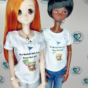 May include: Two dolls wearing white t-shirts with a graphic print that says "Not Marked Safe From Smart Doll Drop". The dolls are wearing jeans and have different skin tones.