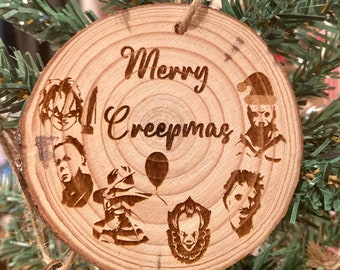 May include: A wooden Christmas ornament with the text "Merry Creepmas" and images of horror movie characters, including Michael Myers, Freddy Krueger, Jason Voorhees, Pennywise, and Leatherface.