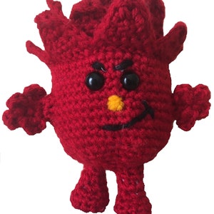 May include: A handmade, red crocheted character with black eyes, a yellow nose, and a smiling mouth. The character has spiky hair, arms, and feet. The toy is made of yarn and has a whimsical design.