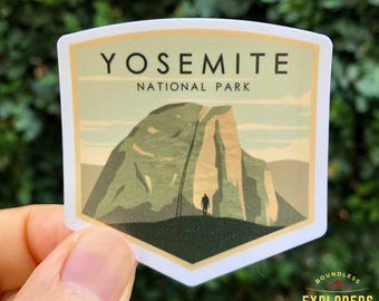 以下が含まれることがあります： ヨセミテ国立公園のハーフドームをヴィンテージスタイルで描いた白いステッカー。ステッカーには「Yosemite National Park」の文字と、トレイルに立っている人のシルエットが描かれています。
