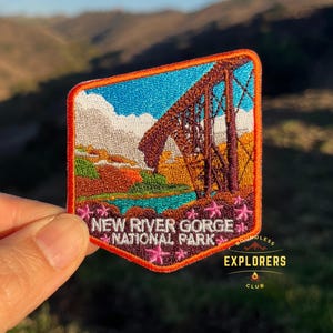May include: A colorful embroidered patch featuring a scenic view of a bridge over a river with a mountain in the background. The patch reads "New River Gorge National Park" and "Boundless Explorers Club".