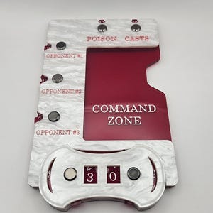 May include: A white pearlescent acrylic game tracker with a deep red center section. It features the text COMMAND ZONE, POISON, CASTS, and labels for OPPONENT #1, #2, and #3. The device includes magnetic markers and two rotating number dials.