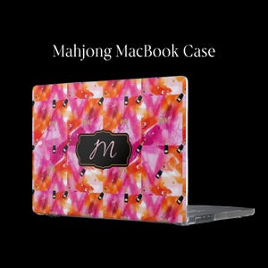 May include: A MacBook case featuring a vibrant pink and orange watercolor pattern with small champagne bottle illustrations. A central black rectangular label with gold trim displays the cursive letter M. The text Mahjong MacBook Case appears.