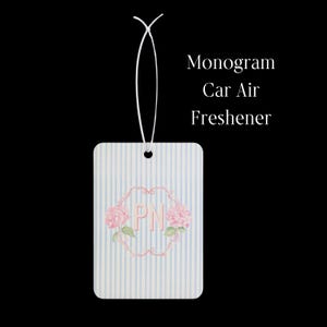 May include: A rectangular car air freshener featuring a light blue and white vertical striped pattern. The center displays the letters PN in pink, framed by a decorative pink border and pink hydrangea flowers. A white string is attached at the top.