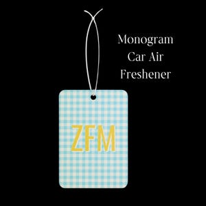 May include: A rectangular car air freshener featuring a light blue and white gingham pattern with the yellow monogram letters ZFM centered on the front. A white elastic string is attached to the top for hanging. The text Monogram Car Air Freshener is visible.
