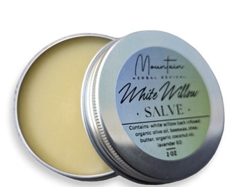 May include: A silver tin with a white label that reads "Mountain Herbal Rejuvenu White Willow Salve". The label also includes the ingredients: white willow bark infused organic olive oil, beeswax, shea butter, organic coconut oil, lavender EO. The tin contains a yellow salve and is labeled 2 oz.