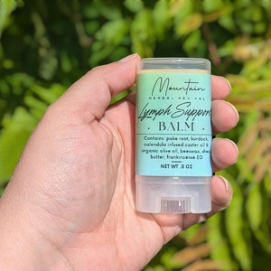 May include: A white tube with a light blue label that reads "Mountain Herbal Revival Lymph Support Balm". The label also includes a list of ingredients and the text "NET WT. 5 OZ".