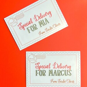 K&ouml;nnte beinhalten: Zwei wei&szlig;e Geschenkanh&auml;nger mit einem Rentier-Motiv und dem Text "Special Delivery" in Rot. Der erste Anh&auml;nger lautet "For Mia" und der zweite Anh&auml;nger lautet "For Marcus". Beide Anh&auml;nger tragen den Text "From Santa Claus" in einer kleineren Schriftart.