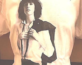 May include: White t-shirt with a black and white photo of Patti Smith on the front. The text "Patti Smith Horses" is printed above the photo.