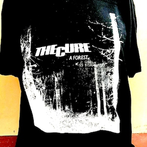 May include: Black t-shirt with a white graphic of a forest and the text "The Cure A Forest."