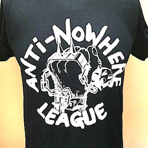 May include: Black t-shirt featuring a white graphic of a hand holding a television with the text "Anti-Nowhere League" around it.