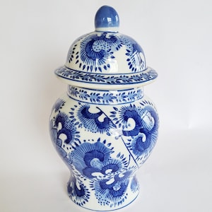 May include: A ceramic ginger jar with a removable lid, featuring a white base decorated with intricate blue floral patterns. The jar has a rounded body, a tapered neck, and a domed lid with a small knob handle, all adorned with blue designs.