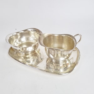 May include: A white ceramic mug with a black handle and the text "But first, coffee" in a handwritten style. The mug is on a white surface. The mug is 10 cm tall.