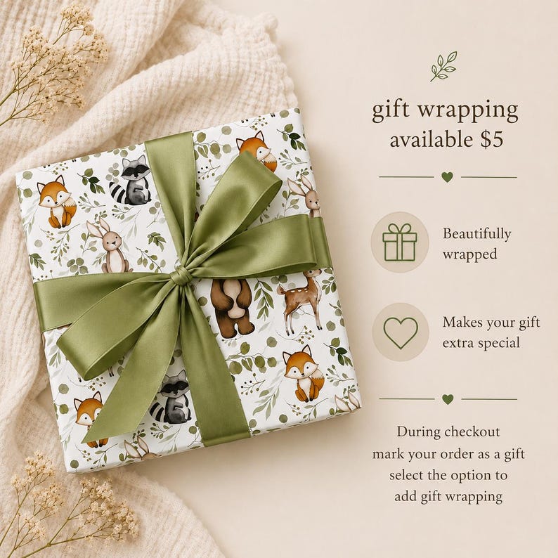 May include: A square gift box wrapped in white paper featuring a pattern of woodland animals including foxes, raccoons, rabbits, and deer with green foliage. The box is tied with a wide olive green satin ribbon bow. Text reads gift wrapping available $5.