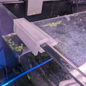 May include: A white 3D printed aquarium accessory for holding a glass rod or other aquarium equipment.